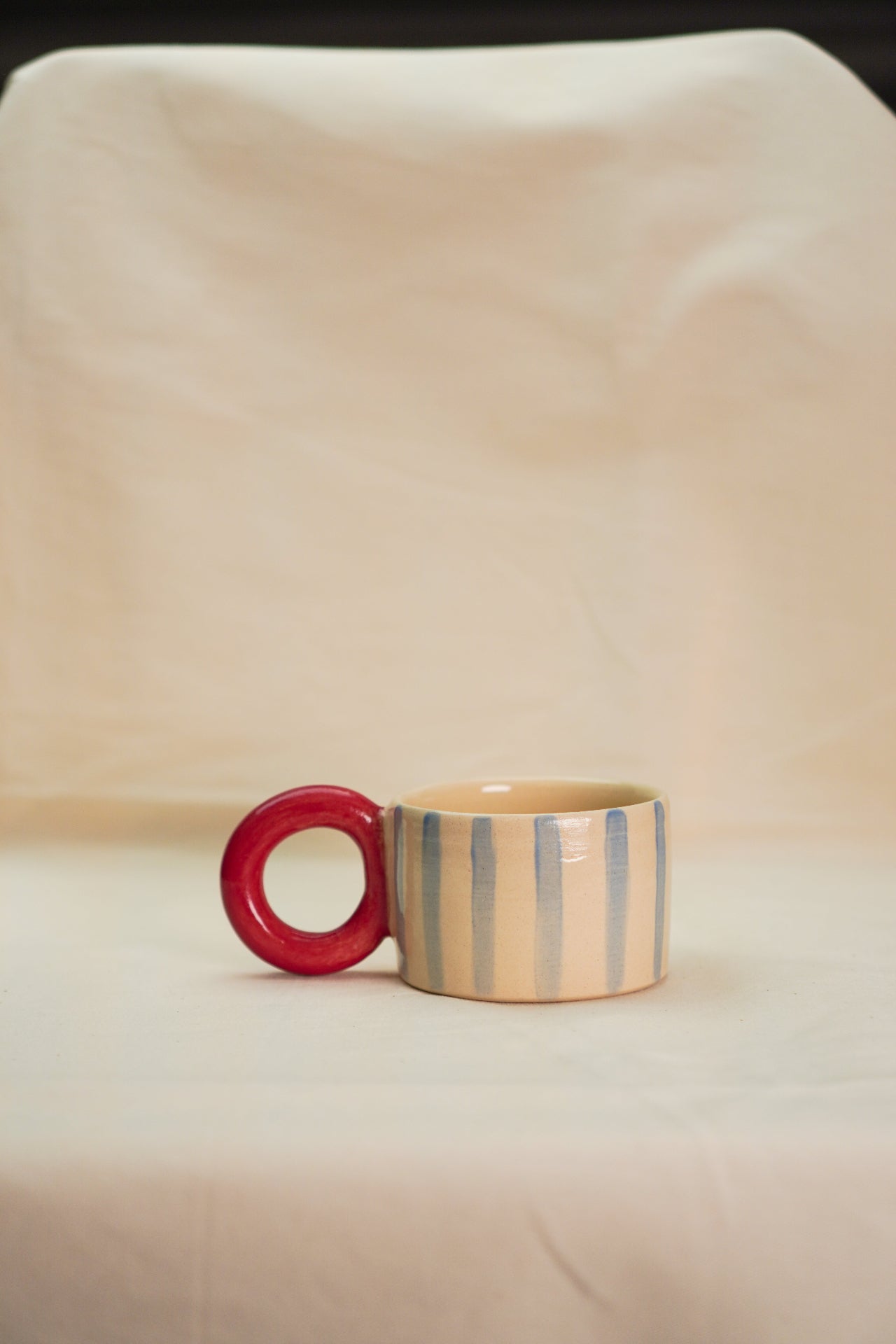 Filiżanki ceramiczna w niebieskie paski z czerwonym uchem kołem.