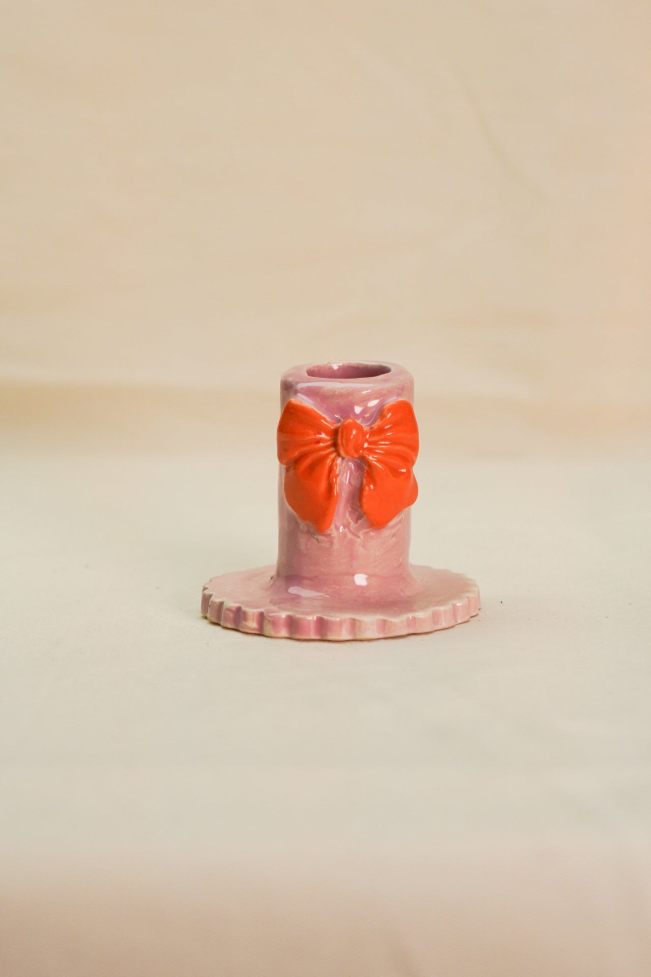 Różowy świecznik z pomarańczową kokardą.